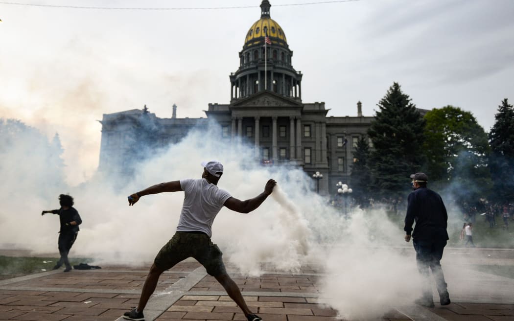 A man throws a tear gas canister back at police officers in front of the Colorado State Capitol as protests against the death of George Floyd continue.