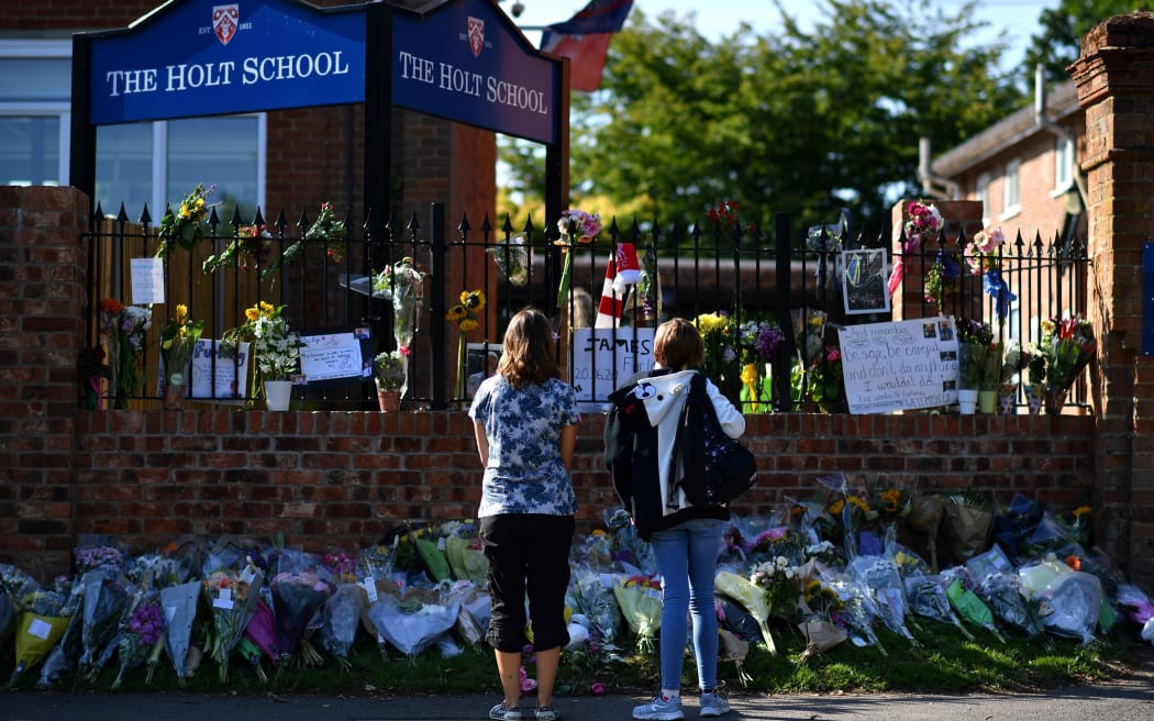 People look at floral tributes left outside The Holt School in Wokingham on June 23, 2020 in memory of teacher James Furlong who was a victim in the knife attack in Reading which killed three people. -