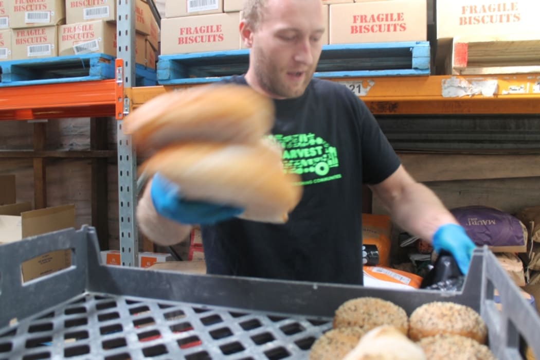 An image of driver Sam Mentink packing unwanted food into a clean black rubbish bag.
