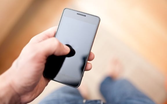 An unseen person uses a smart phone to send a text message.