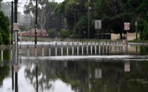 A main road is blocked by flood waters on the bank of Georges river on March 3, 2022, as Sydney faces its worst flooding after record rainfall caused its largest dam to overflow