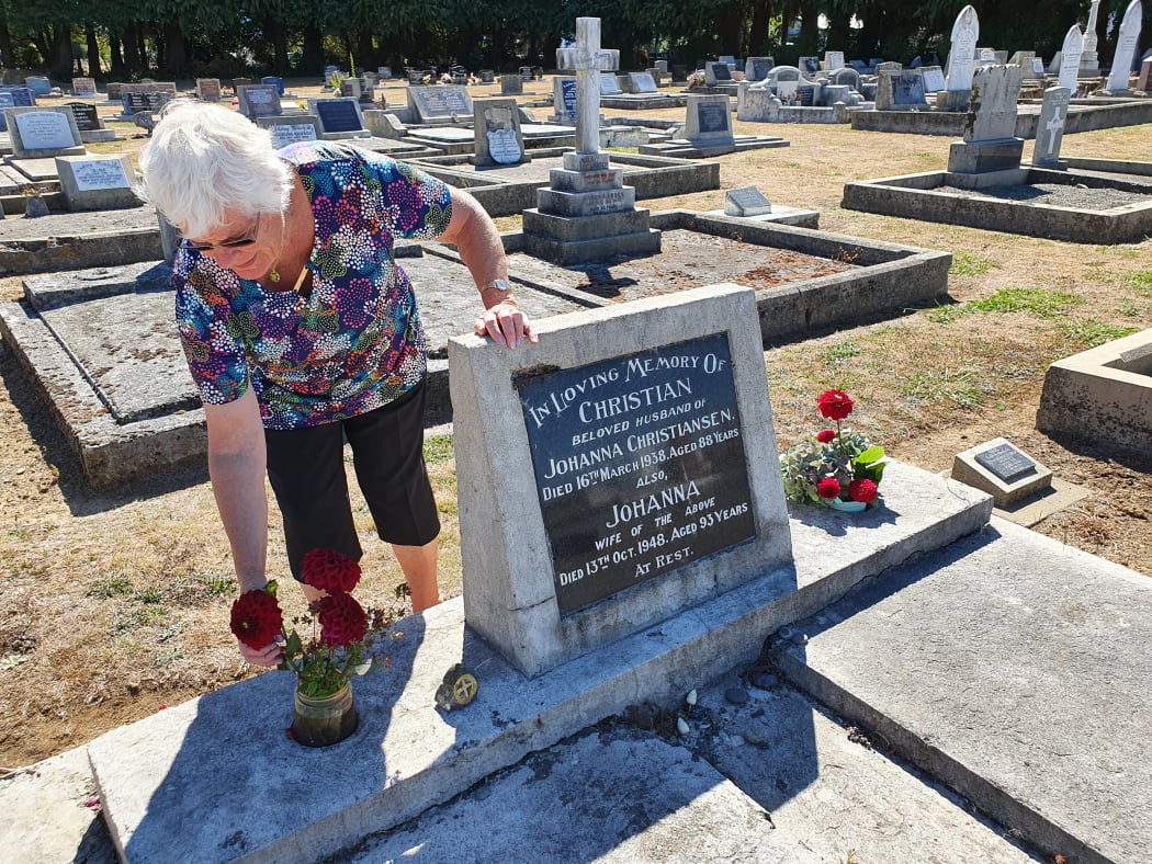 Heather Cheer places red flowers and a symbol of the scandi wheel on one of the graves of Scandinavian settlers at the Norsewood Cemetery