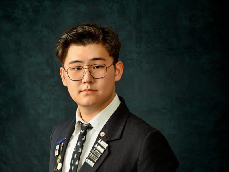 Pinehurst School student Kevin Guo in his school uniform, wearing glasses, for a portrait.