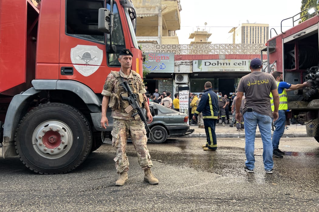 A Lebanese army soldier stands guard near fire trucks at the scene of a reported pager device explosion in Saida in southern Lebanon on September 18, 2024. A second wave of device explosions killed three people in Hezbollah strongholds of Lebanon on September 18, raising fears of an all-out war between Israel and the Iran-backed militants. (Photo by Mahmoud ZAYYAT / AFP)