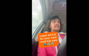 A screenshot of a TikTok. Tyrone is driving a car in a pink suit. Text appears over him saying "LEGAL ADVICE FOR YOUR NEXT ROAD TRIP WEE".