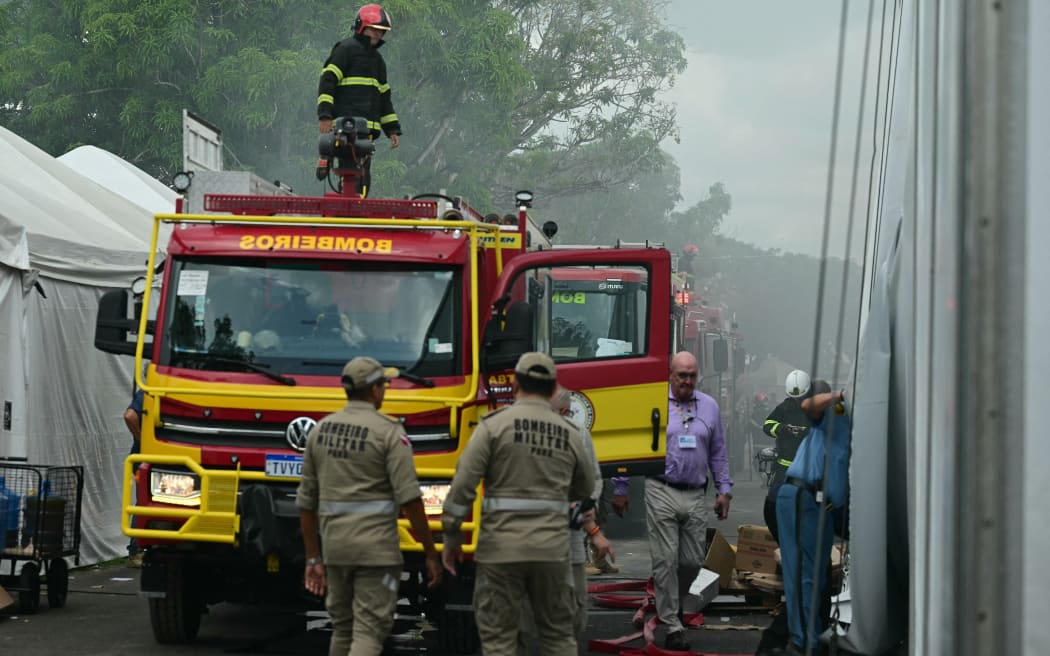 Firefighters battle a fire that broke out in a pavilion at the COP30 UN Climate Change Conference venue in Belem, Para state, Brazil on November 20, 2025. A fire erupted at a pavilion inside the venue of the UN's climate talks in Brazil on Thursday, prompting panicked delegates to run for the exits, AFP journalists said. Emergency crews rushed to try to put out the blaze as smoke engulfed the corridor. (Photo by Pablo PORCIUNCULA / AFPTV / AFP)