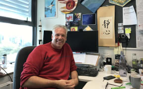 Dr. Nicholas Rattenbury in his office, with a rocket model behind him.