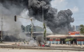 Protesters gather near burning buildings and barricades as clashes erupt in Dar es Salaam on 29 October, 2025, during Tanzania’s presidential elections.