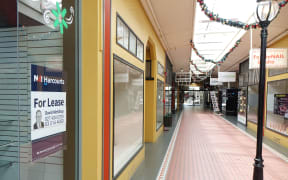 Looking down arcade with two empty shop fronts on the left.