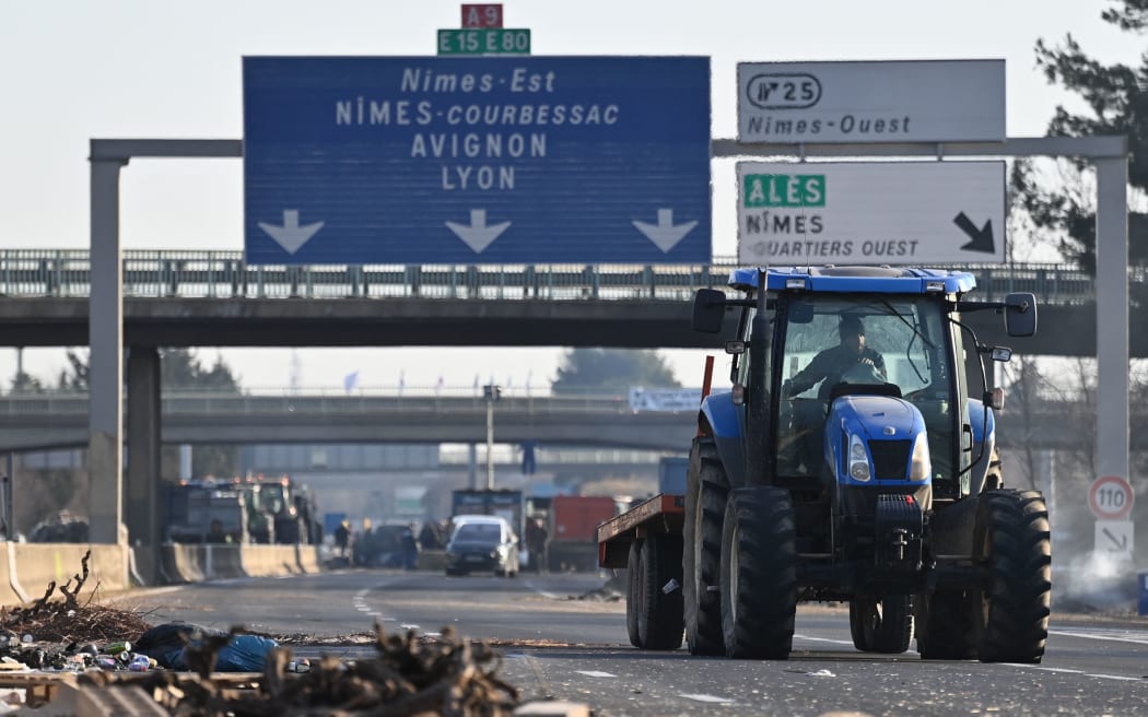 A farmer drives a tractor as French farmers take part in a road block protest on the A9 highway in Nimes, southern France, on January 29, 2024, amid nationwide protests called by several farmers unions on pay, tax and regulations. France's main farmers' unions decided to continue their mobilization, after roadblocks and protests across the country, deeming the French Prime Minister's announcements insufficient. (Photo by Sylvain THOMAS / AFP)