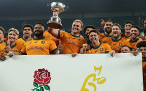 Australia's captain Harry Wilson holds the Ella-Mobbs Trophy as Australia's players pose after their win in the Autumn Nations Series International rugby union test match between England and Australia at the Allianz Stadium, Twickenham in south-west London, on November 9, 2024. - Australia won the game 42-37. (Photo by Adrian Dennis / AFP)