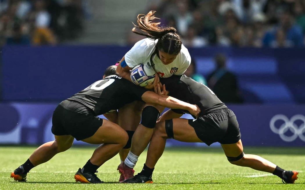 US' Ilona Maher (C) is tackled by New Zealand's Theresa Setefano (L) and New Zealand's Risi Pouri-Lane (R) during the women's semi-final rugby sevens match between New Zealand and USA during the Paris 2024 Olympic Games at the Stade de France in Saint-Denis on July 30, 2024. (Photo by CARL DE SOUZA / AFP)