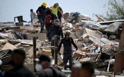 Rescue workers walk across the rubble of collapsed buildings during search efforts following an earthquake in Catia La Mar, La Guaira state, about 30 km northwest of Caracas, on June 25, 2026. A twin earthquake that was Venezuela’s largest in over a century has killed at least 164 people and destroyed multiple buildings near the capital, where residents searched on June 25 for missing relatives. (Photo by Juan BARRETO / AFP)