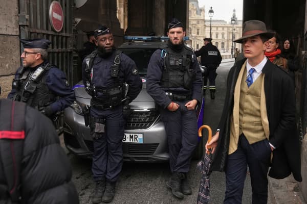 Pedro Elias Garzon Delvaux, right, walks past as police officers block an entrance to the Louvre after thieves carried out a daylight raid on French crown jewels, in Paris on 19 October.