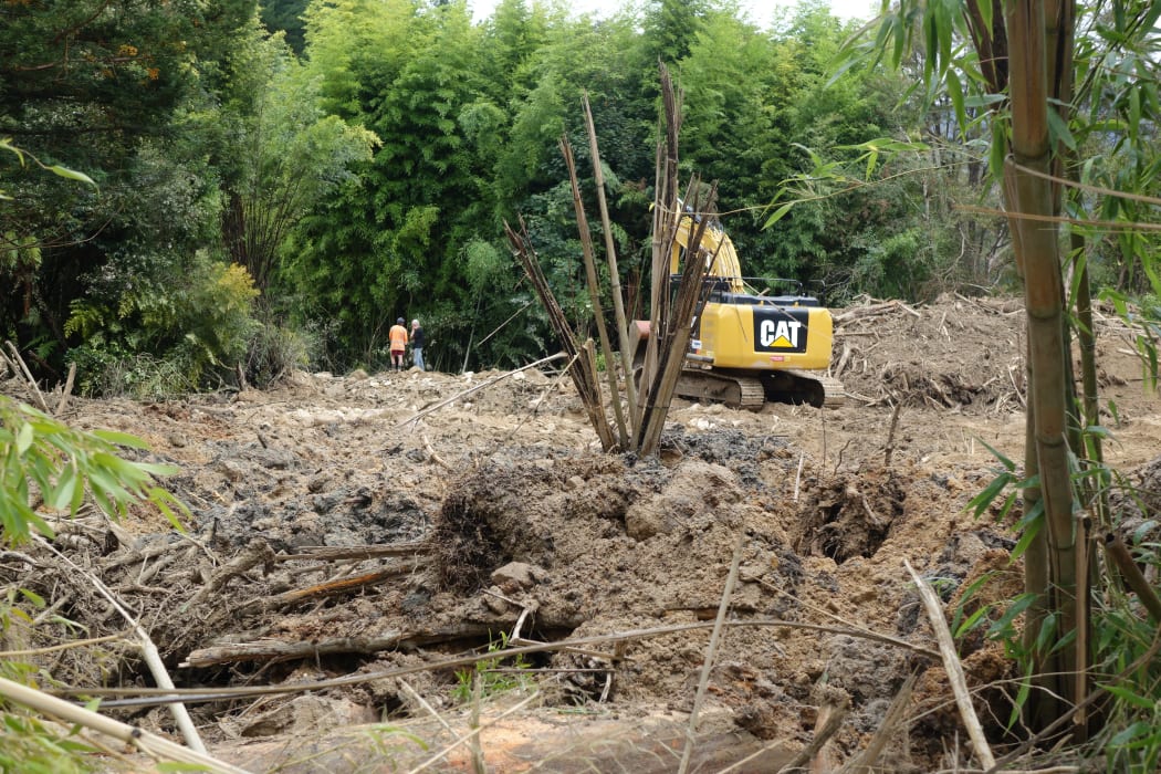 A digger helps clear forestry debris in Marahau after slips and flash flooding from Cyclone Gita.