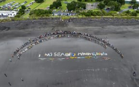 No seabed mining written on the beach with boards and canoes