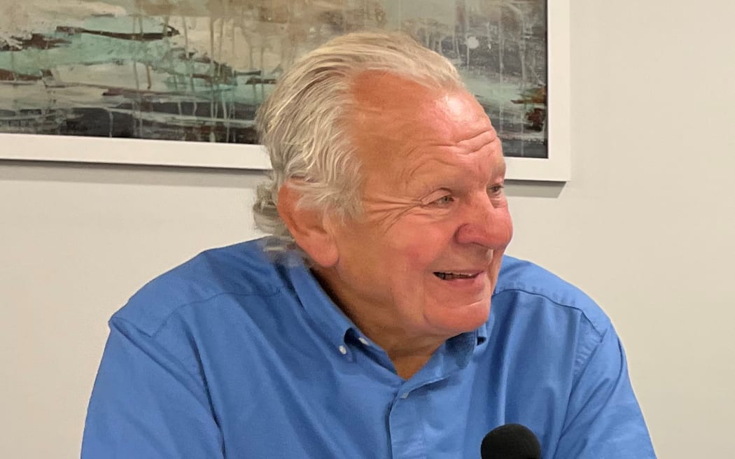 A photo of World Rugby Chairman, Sir Bill Beaumont, wearing a blue shirt with a microphone in front of him.