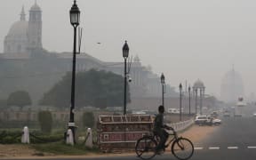 A man rides a bicycle along a street under heavy smog in New Delhi on October 29, 2019. (Photo by Jewel SAMAD / AFP)