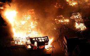 This aerial photo shows buildings burning in the city of Wajima, Ishikawa prefecture on 1 January, 2024, after a major earthquake struck Japan's Noto region. Tsunami waves over a metre high hit central Japan on after a series of powerful earthquakes that damaged homes, closed highways and prompted authorities to urge people to run to higher ground.