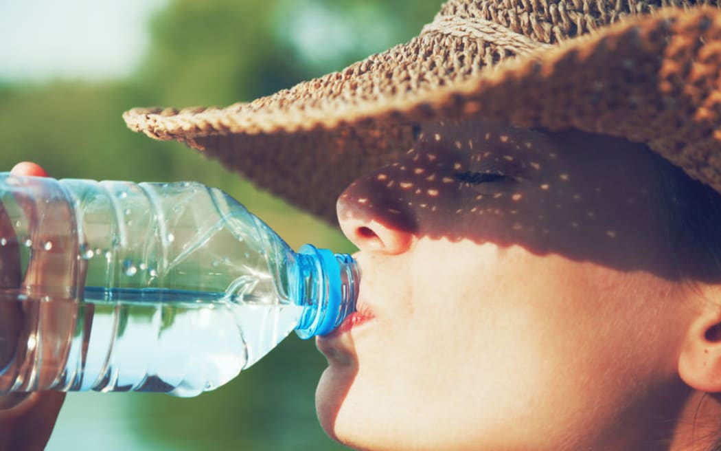 Woman drinking water in summer sunlight