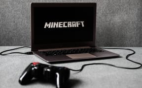 Minecraft logo displayed on a laptop screen and a gamepad are seen in this illustration photo taken in Krakow, Poland on August 5, 2021.