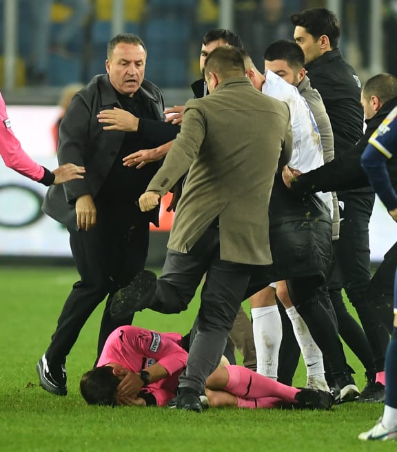 Turkish Referee Halil Umut Meler (ground) cover itself as MKE Ankaragucu's president Faruk Koca (L) attacks him at the end of the Turkish Super Lig football match.
