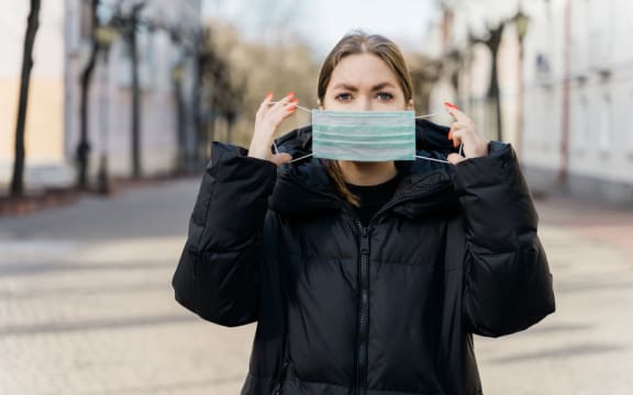 Female put on face mask protection virus covid-19 travel European city street. Concept health and safety, N1H1 coronavirus, virus protection