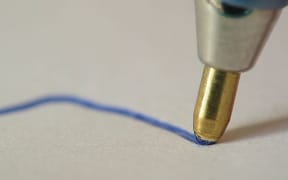 Ballpoint pen writing. Streaks of ink are visible on the ball, indicating the direction of rotation.