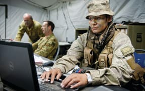 Member of the New Zealand Defence Force on a laptop in uniform