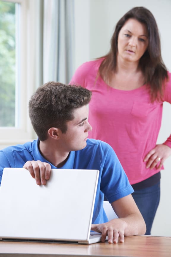 A photo of a guilty Teenage Boy Hiding Internet Browsing From Mother