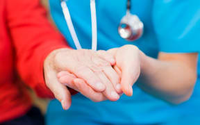 A doctor holds an elderly woman's hand