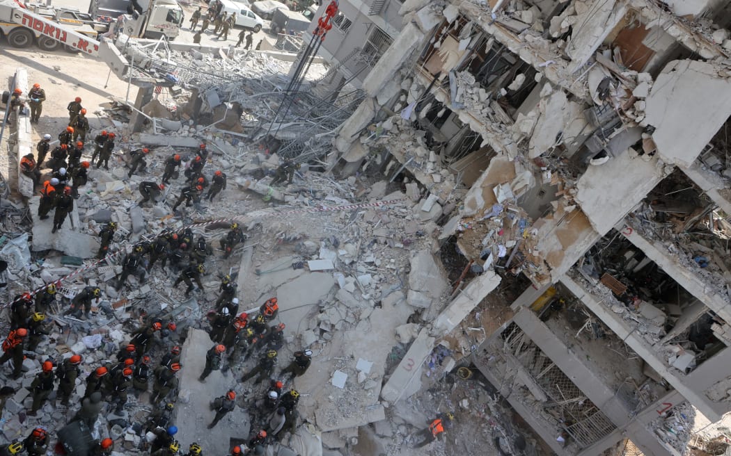 Israeli rescuers search through the rubble of a heavily damaged building, following an overnight Iranian missile strike in Bat Yam on June 15, 2025. Israeli Prime Minister Benjamin Netanyahu said that Iran would pay "a very heavy price" for killing Israeli civilians, during a June 15 visit to the site of a missile strike on a residential building near Tel Aviv, as the two foes kept up intense fighting. (Photo by GIL COHEN-MAGEN / AFP)