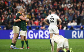 England's George Ford looks on as Faf de Klerk and Vincent Koch embrace as they celebrate South Africa's victory at the end of the Rugby World Cup semi-final match between England and South Africa at the Stade de France.