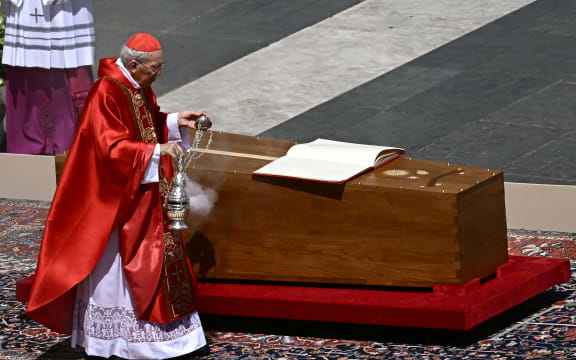 Italian cardinal Giovanni Battista Re swings an incense burner towards the coffin of late Pope Francis with the book of the gospels displayed on it during the funeral ceremony at St Peter's Square in The Vatican on April 26, 2025. (Photo by Filippo MONTEFORTE / AFP)