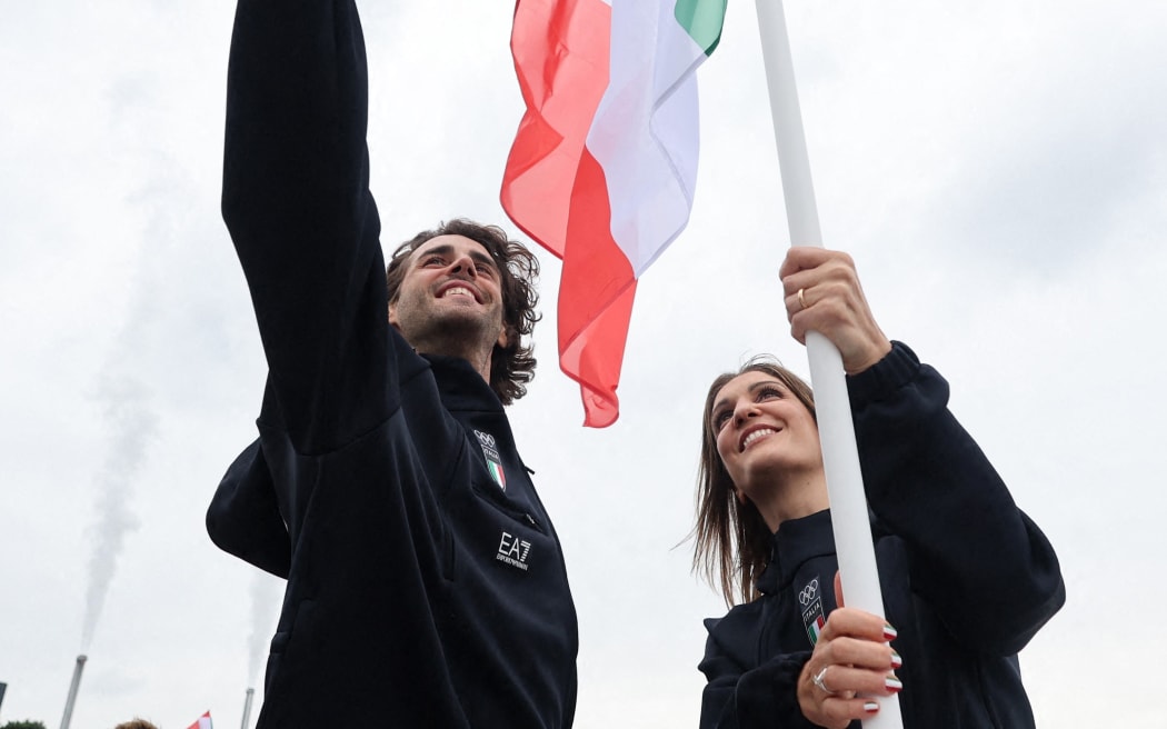 Paris 2024 Olympics - Opening Ceremony - Paris, France - July 26, 2024. Flagbearers Arianna Errigo and Gianmarco Tamberi of Italy take a selfie aboard a boat in the floating parade on the river Seine during the opening ceremony. (Photo by Nir Elias / POOL / AFP)