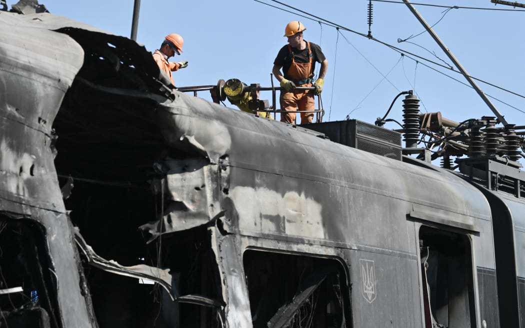 Employees repair a power supply line over an Intercity+ high-speed train heavily damaged in a depot during a large-scale Russian drone and missile attack on Kyiv, on 28 August, 2025.