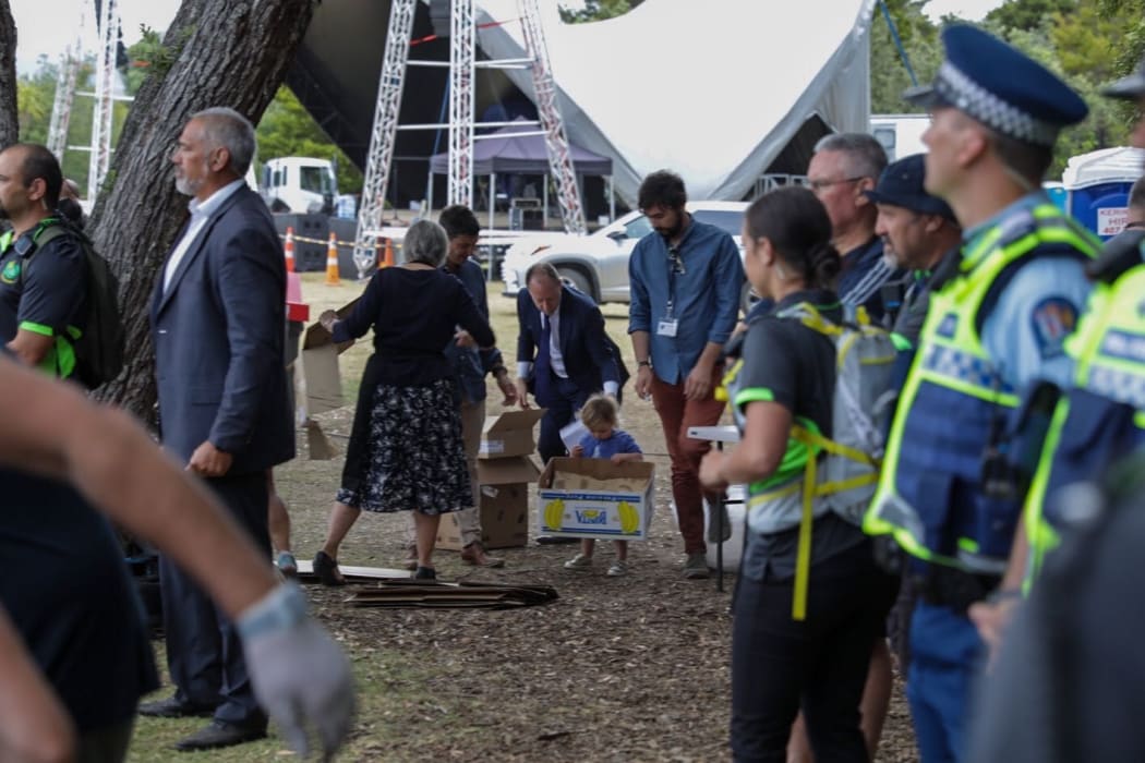 Baby Neve playing with boxes at Waitangi as dad Clarke Gayford watches her.