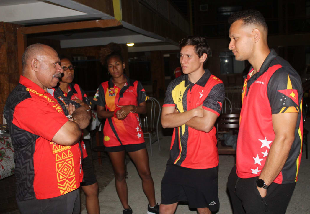 PNG Football Association President John Kapi Natto (L) speaking with Kapuls players David Browne and Alwin Komolong during the 2019 Pacific Games.