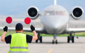 An air traffic controller guides a plane on a runway.