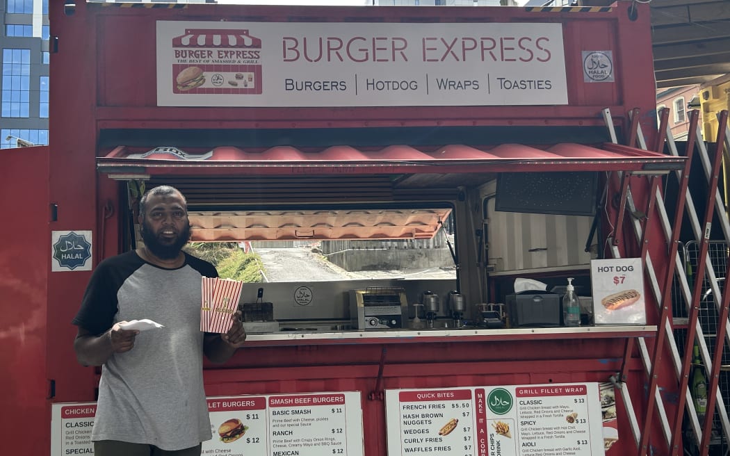 A man holding a pile of receipts and a burger box.