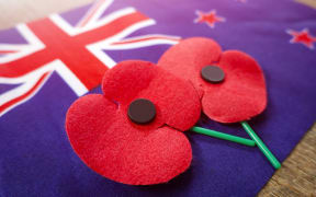 Close up on Remembrance poppies on a New Zealand flag.