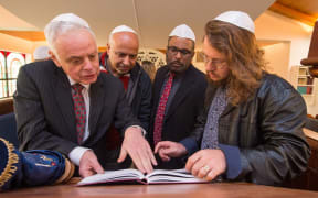 New Zealand Jewish Council president Stephen Goodman (front left) and Asher Levi Etherington (front right) show Muslim visitors a Torah at a Christchurch Synagogue.