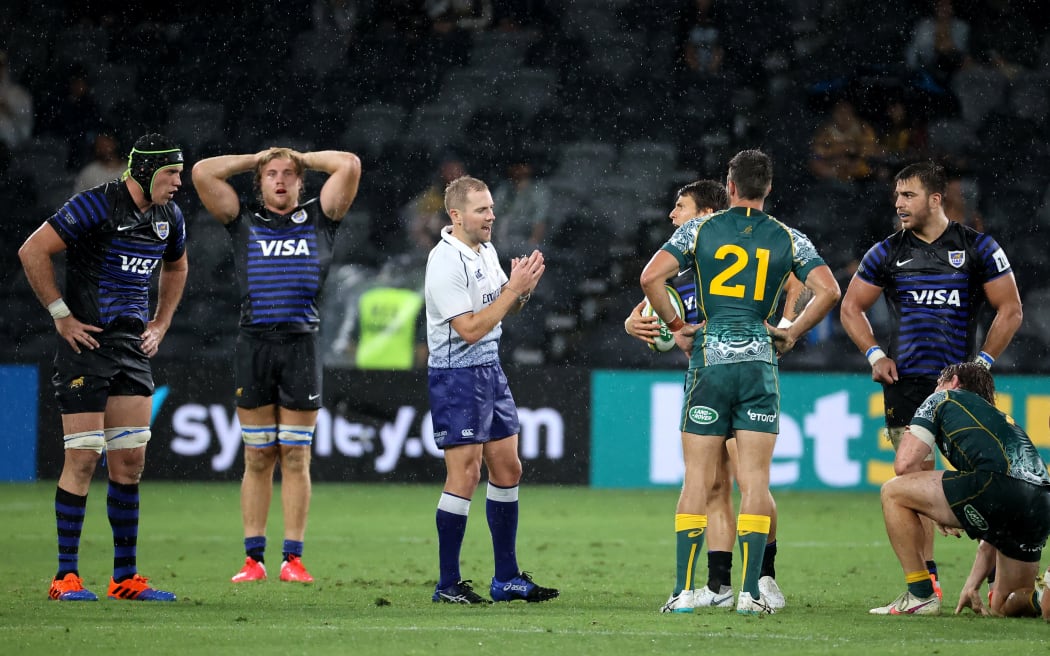 Australian and Argentinian players react as referee Wayne Barnes (C) blows the final whistle during the 2020 Tri-Nations rugby match between the Australia and Argentina in Sydney on December 5, 2020. (