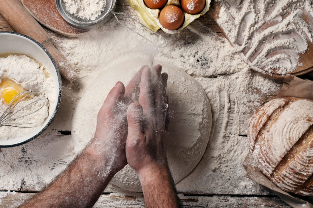 Male baker slaps on dough. Male baker prepares bread. Making bread. Top view. Rustic style
