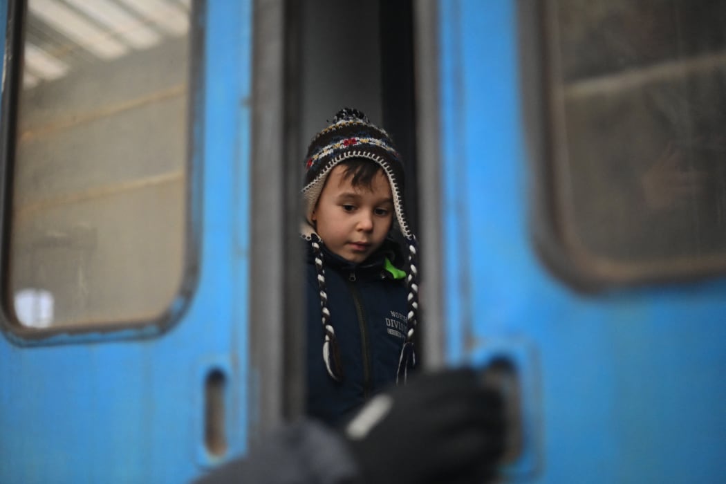 A child looks on as an operator closes the door of a train taking evacuees to Poland, at Lviv train station, western Ukraine, on 5 March 2022.