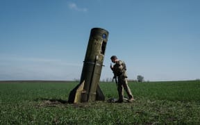 A Ukrainian serviceman looks at a Russian ballistic missile's booster stage that fell in a field in Bohodarove, eastern Ukraine, on April 25, 2022.