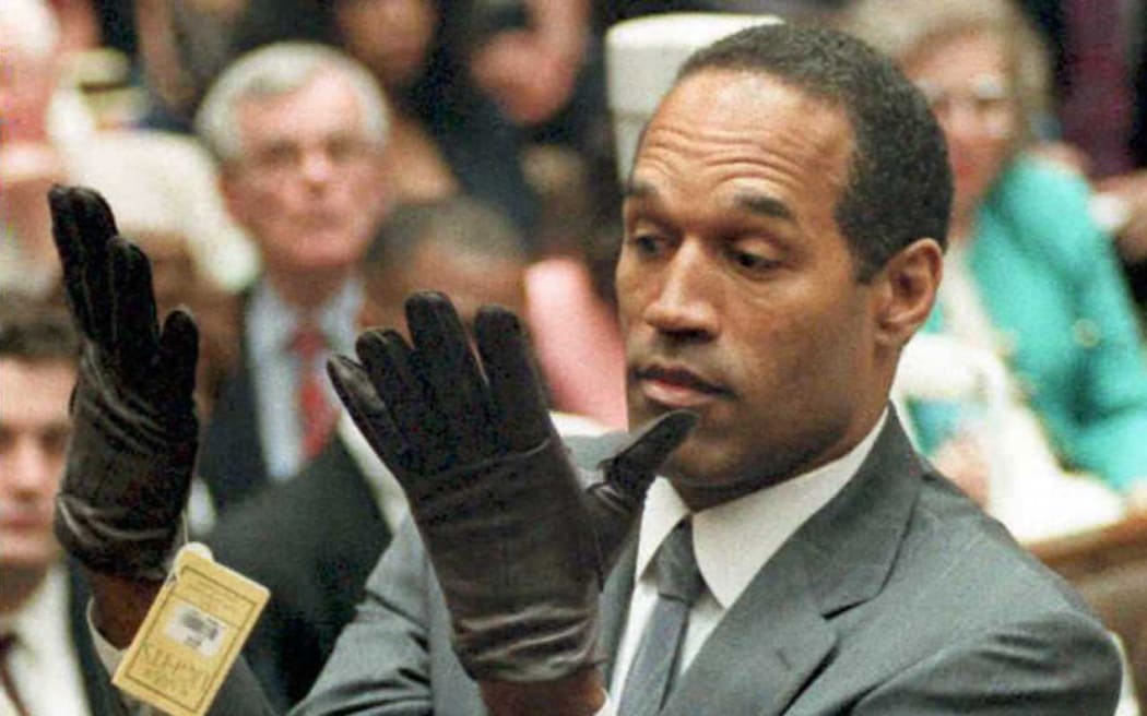 (FILES) O.J. Simpson shows the jury a new pair of Aris extra-large gloves, similar to the gloves found at the Bundy and Rockingham crime scene 21 June 1995, during his double murder trial in Los Angeles, California. Simpson has died at the age of 76, his family said on April 11, 2024. (Photo by VINCE BUCCI / POOL / AFP)