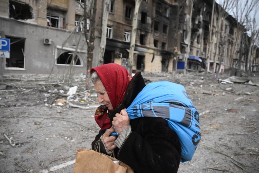 8161100 08.04.2022 An elderly woman passes by a destroyed house in Mariupol, Donetsk People's Republic. Ilya Pitalev / Sputnik (Photo by Ilya Pitalev / Sputnik / Sputnik via AFP)
