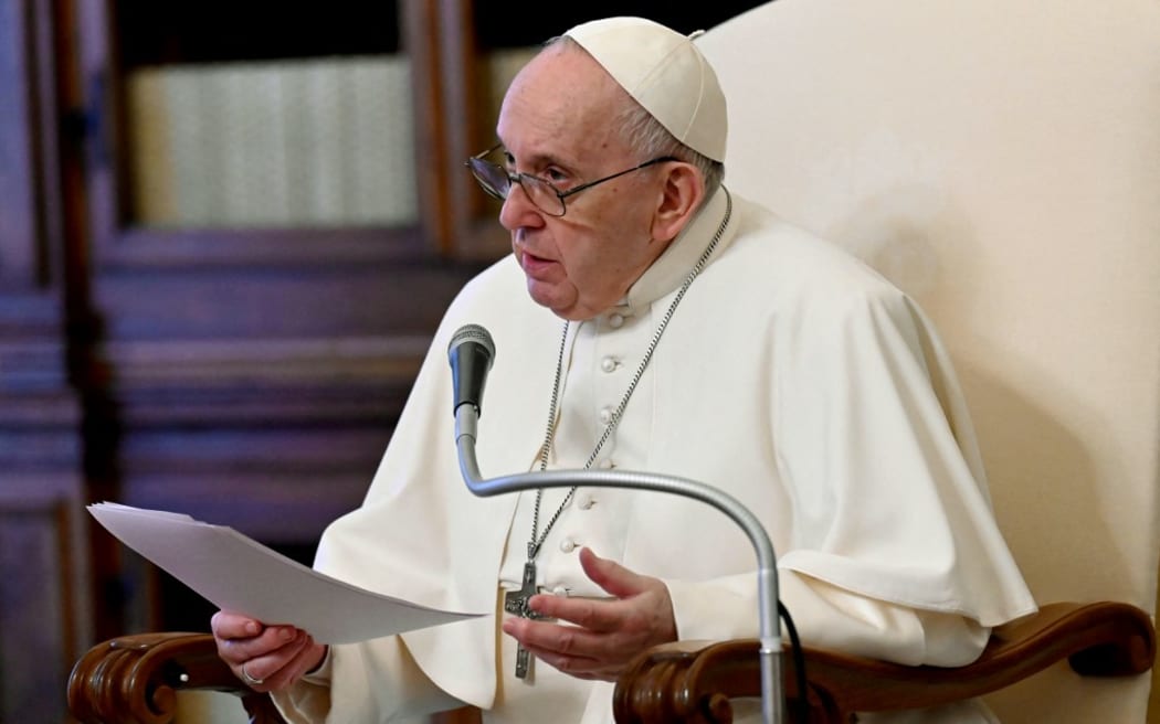 This handout photo taken and released on April 28, 2021 by the Vatican Media shows Pope Francis, delivering his message during a live streamed weekly private audience in the library of the apostolic palace, in The Vatican.