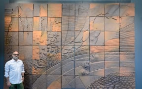 Taupō businessman Chris Johnston with the Barry Brickell clay mural he saved from demolition.